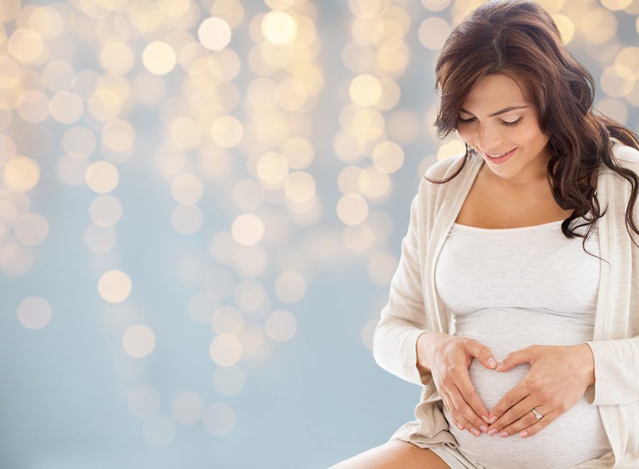 Photo of smiling pregnant woman touching stomach
