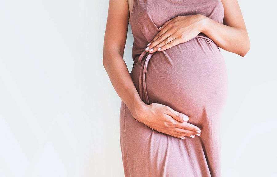 Photo of pregnant woman asleep on bed with hands around stomach