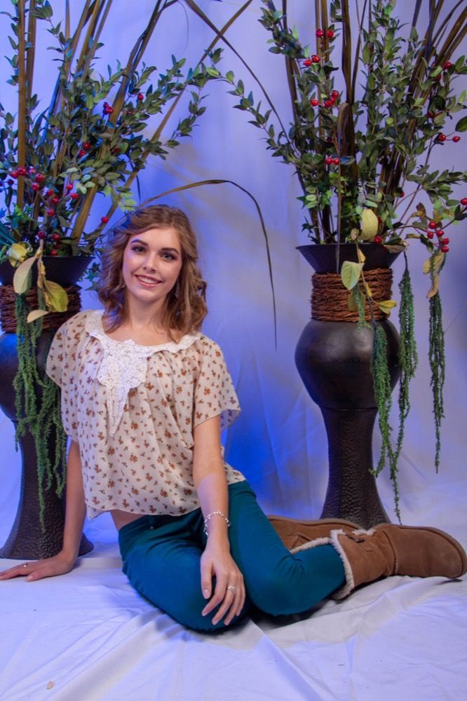 Portrait photograph of woman sitting between vases with flowers