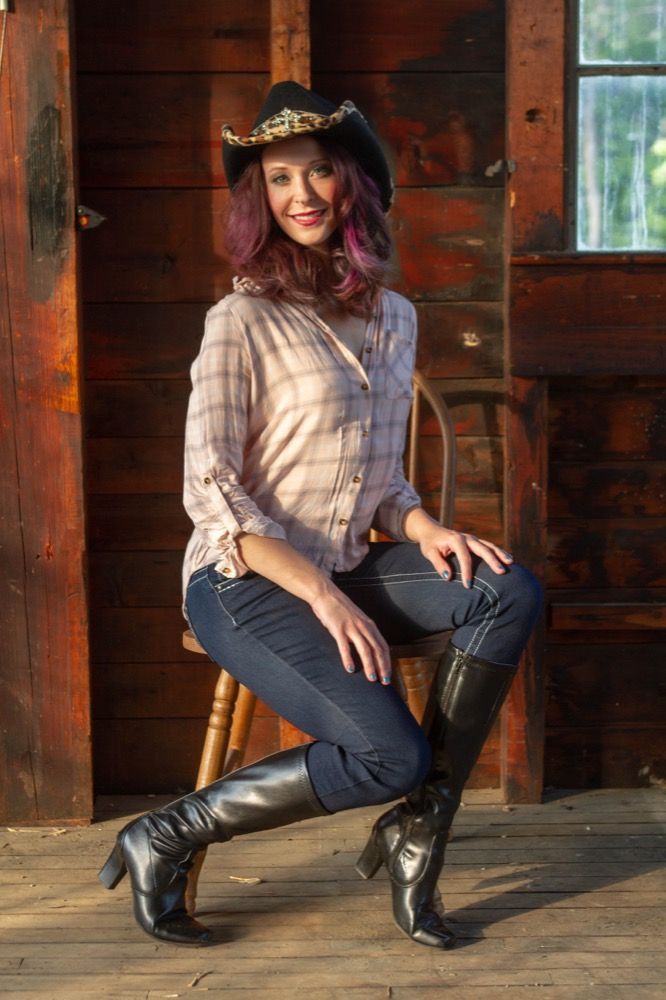 Portrait photograph of woman in cowboy hat sitting on stool