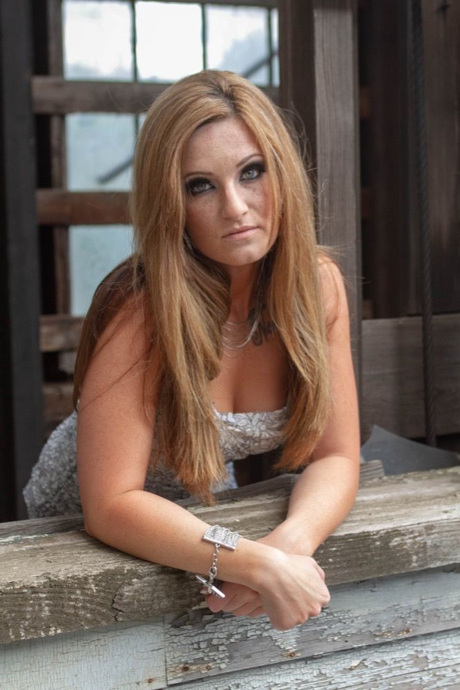 Portrait photograph of woman leaning over wall